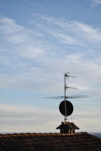 TV and satellite antennas on a rooftop in Bergamo, Italy, with a clear blue sky.